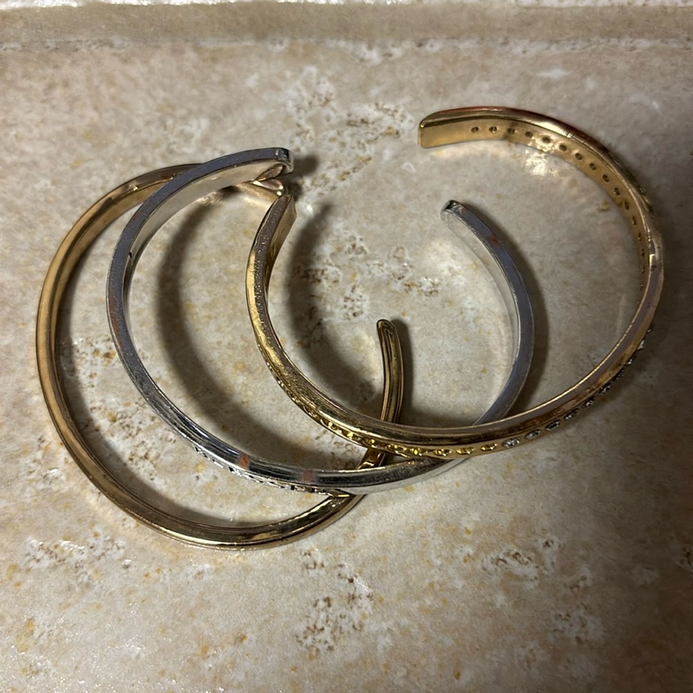 Tri-color (silver, gold and rose gold toned) open bangle bracelets.
